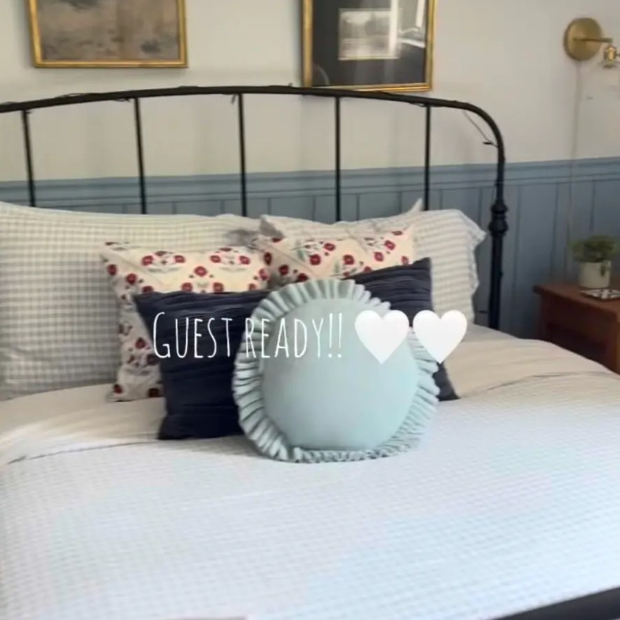 Guest-ready cottage bedroom with iron bed frame and layered bedding