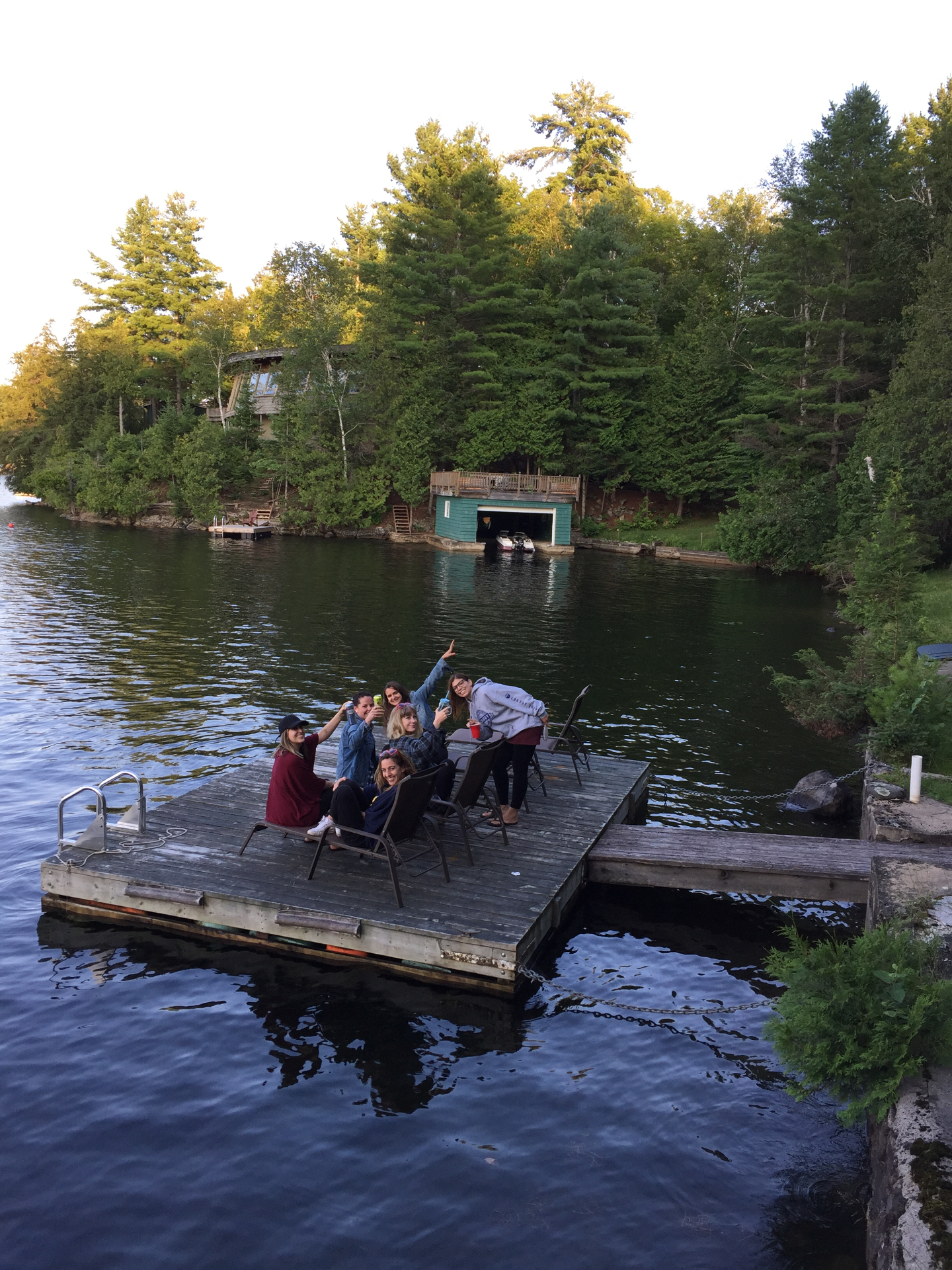 Friends toasting on a lakeside dock at golden hour